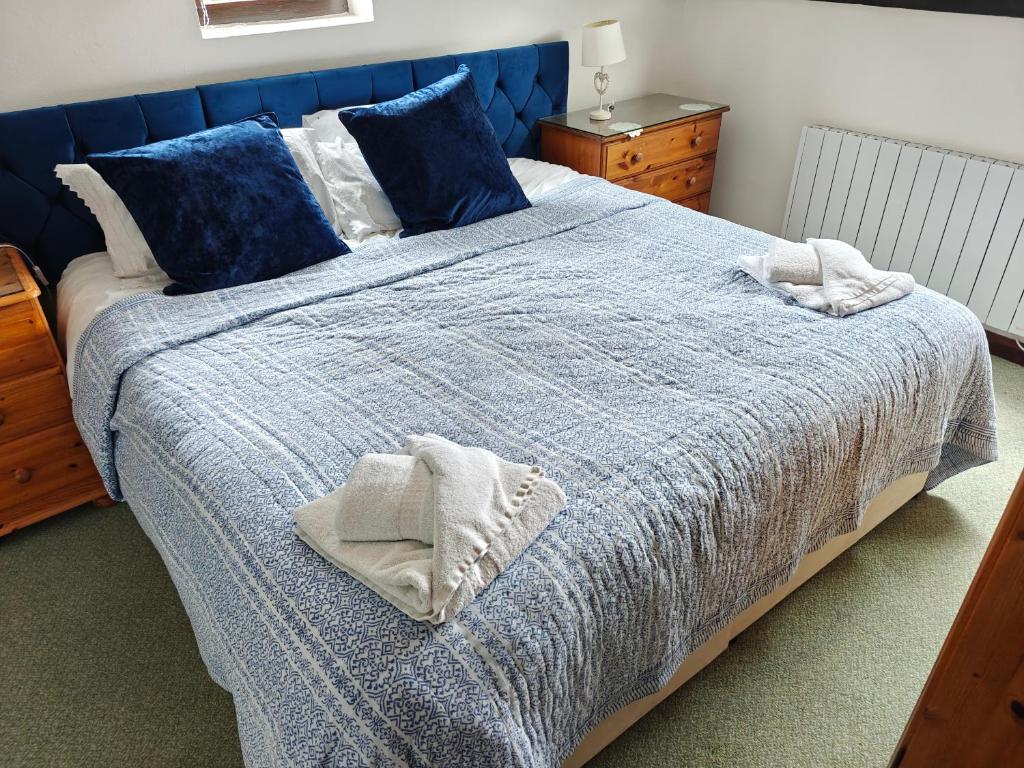ein Schlafzimmer mit einem blauen Bett mit blauen Laken und Kissen in der Unterkunft Linhay -Farm Cottage in Sidmouth