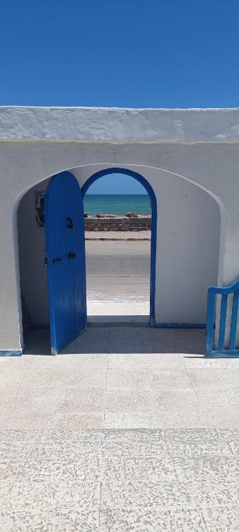 an archway with a blue door on the beach at La Brise de Djerba, Villa de Charme en bord de mer à Al Jazira in Mezraya