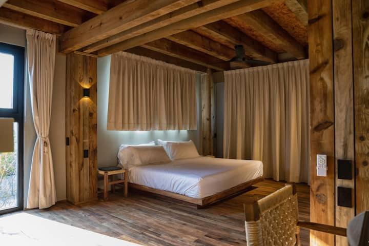 a bedroom with a bed in a room with wooden floors at Kineki 8 in Brisas de Zicatela