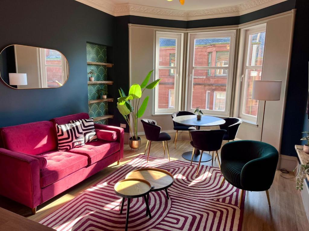 a living room with a red couch and a table and chairs at Townhead Jewel by Coorie Doon Stays in Paisley