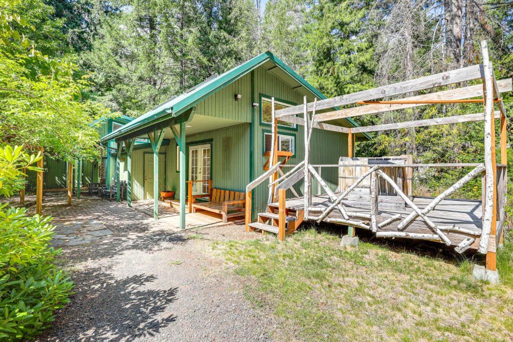 a green house with a porch and a fence at Spring-Fed Soaking Tub! Lush Central Oregon Haven in McKenzie Bridge
