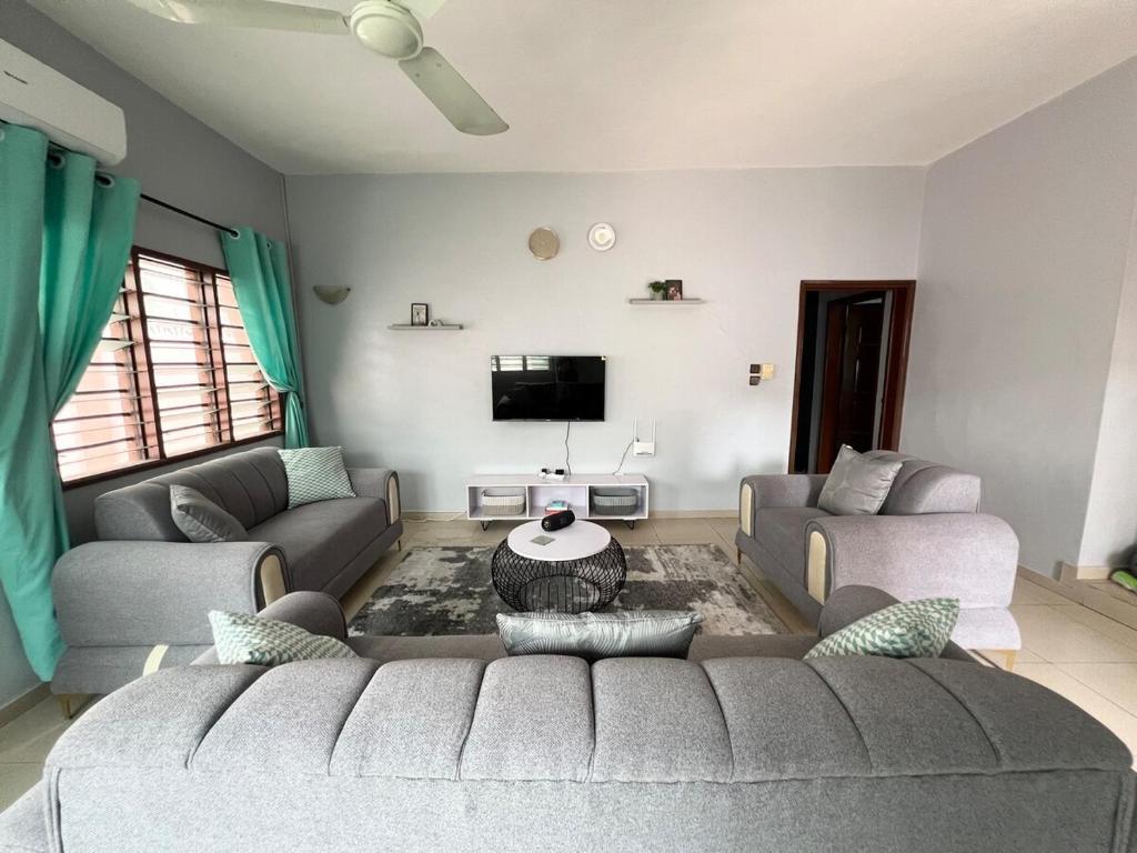a living room with a couch and a tv at Maison entière - La Casa Cotonou in Cotonou