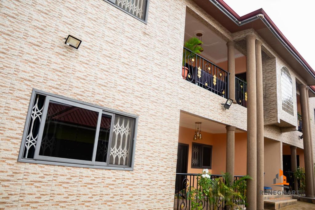 a brick building with a window and a balcony at ReneGhart Apartments in Kasoa