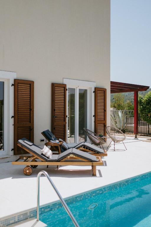 a pool with two lounge chairs next to a house at Villa Aurelia by Domus Mirus - Rooftop Cinema & Pool & 6 Minute Walk to Beach in Splitska