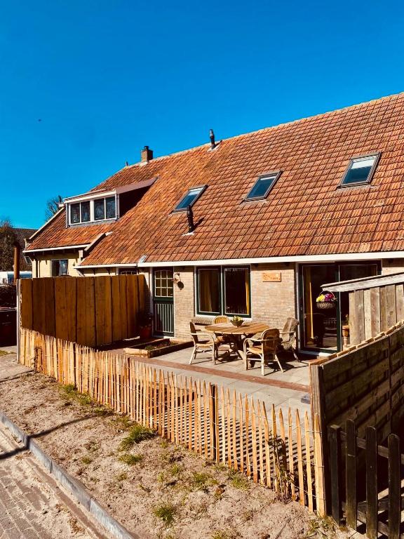 a house with a wooden fence in front of it at BijOpaenOma in Oosterend