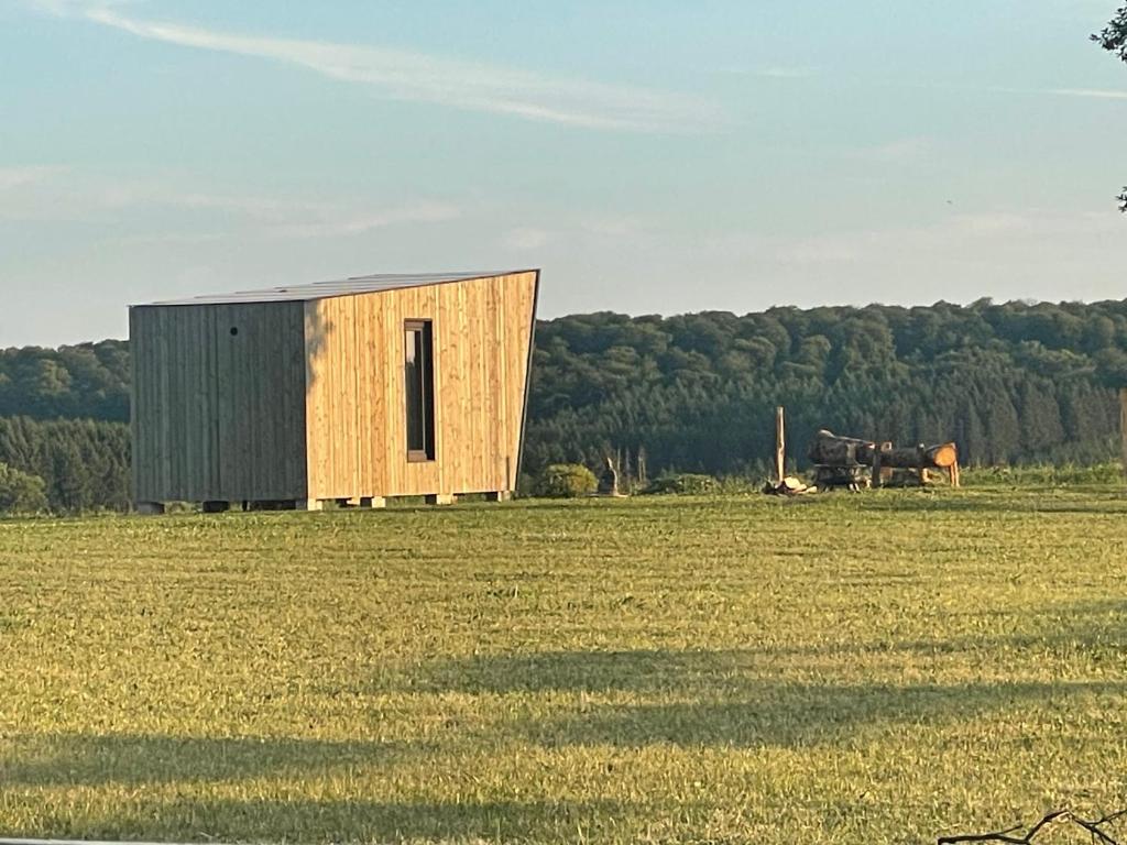un pequeño edificio de madera en un campo de césped en Lalouette, en Porcheresse
