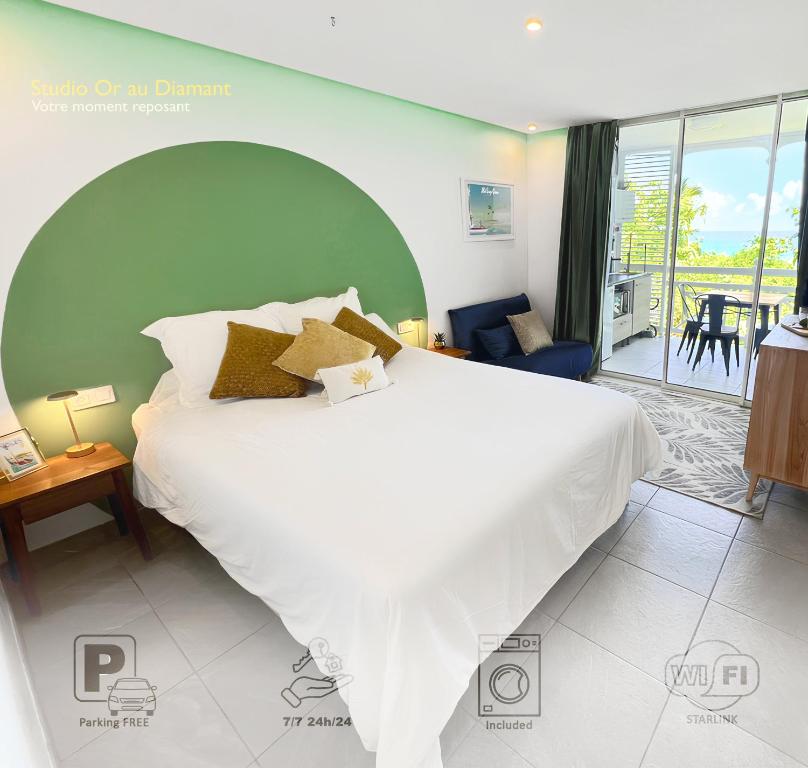 Un dormitorio con una gran cama blanca y un balcón. en Studio Or au Diamant, vue mer des Caraïbes, en Le Diamant