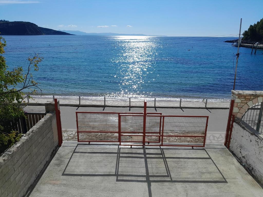 a red bench sitting on the side of a beach at Spiro Guest House in Himare