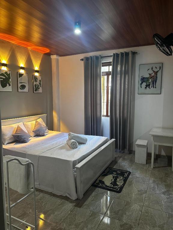 a bedroom with a bed and a table in it at Hotel Halona in Kandy