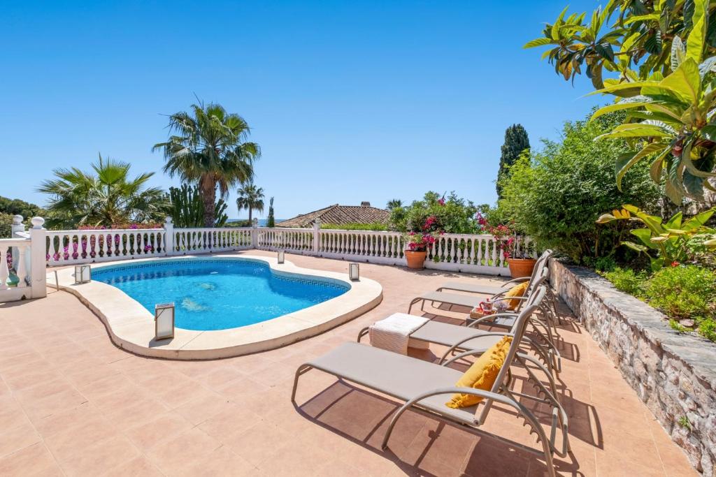 a swimming pool with lounge chairs next to a fence at Casa May in La Cala de Mijas