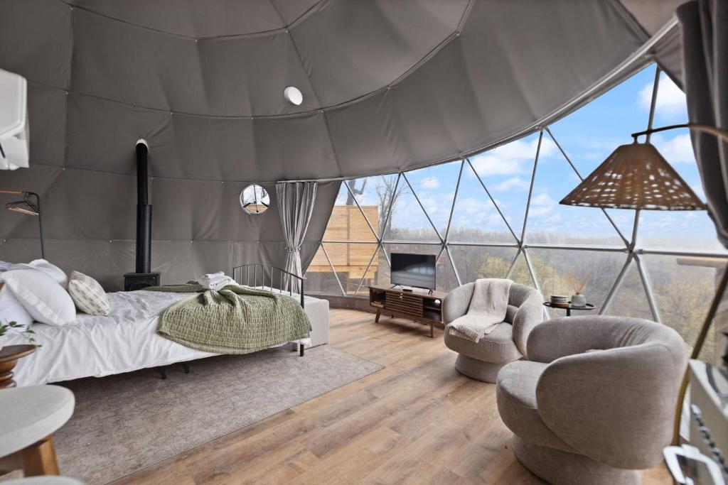 ein Schlafzimmer mit einem Bett und zwei Stühlen und einem Fernseher in der Unterkunft "Bluegrass Bluff" - The Overlook LUX Dome - RRG in Stanton