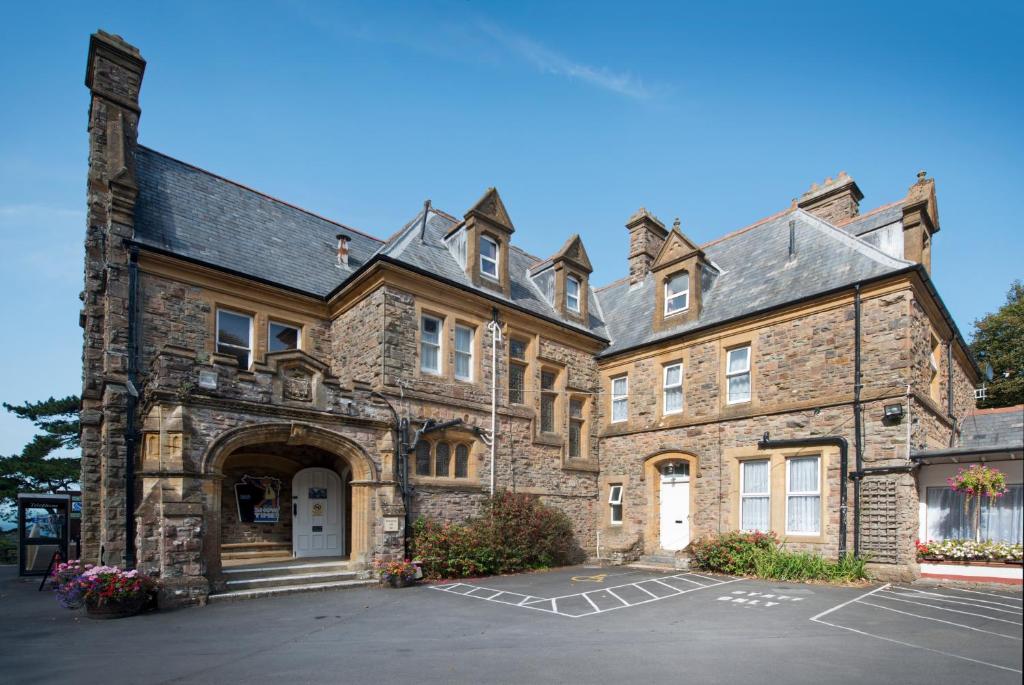 a large stone building with a parking lot at Combe Martin Beach Holiday Park in Combe Martin