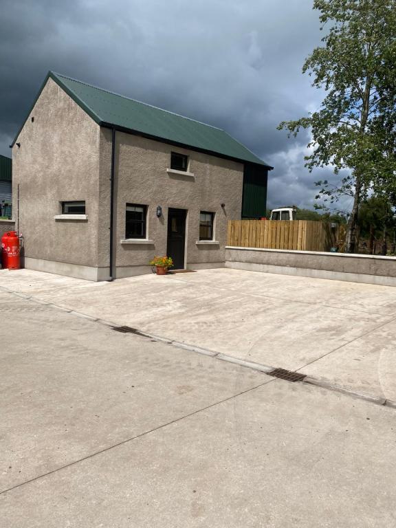 un grand bâtiment en briques avec un toit vert dans l'établissement The Cottage Gortfad, à Garvagh