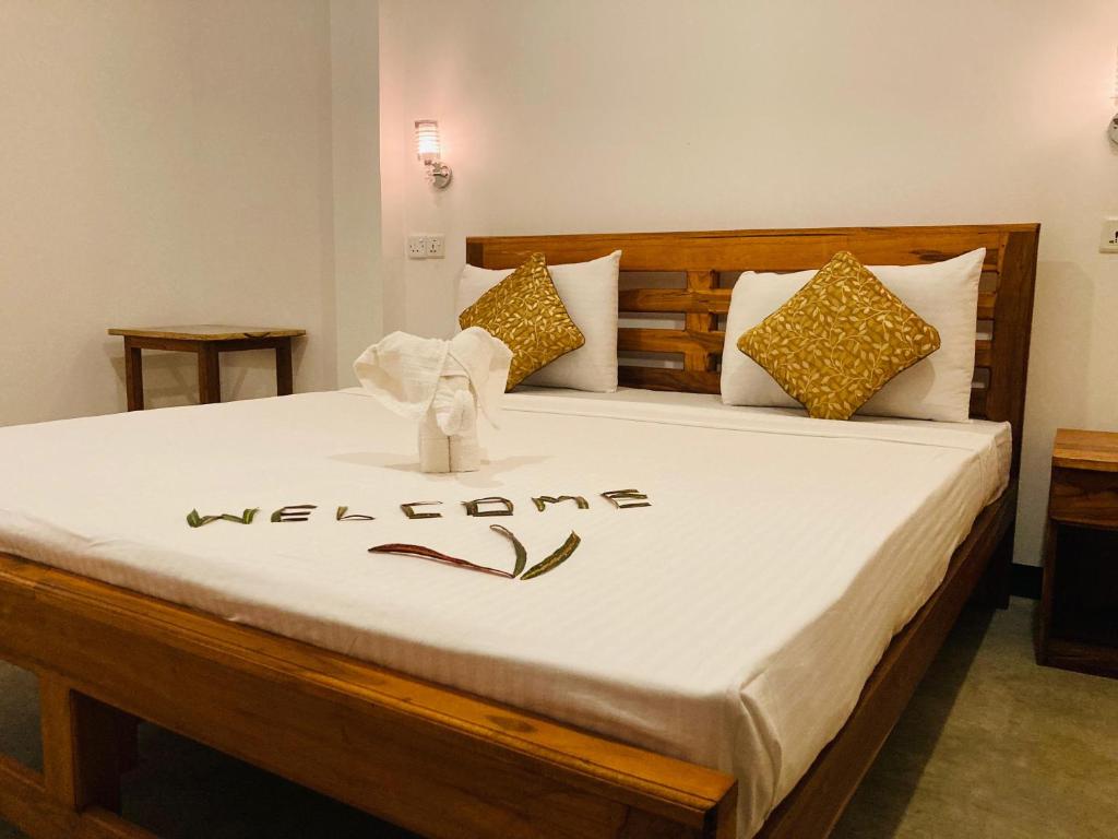 - une chambre avec un lit et un panneau de bienvenue dans l'établissement Wild Safari River Cottage udawalawe, à Uda Walawe
