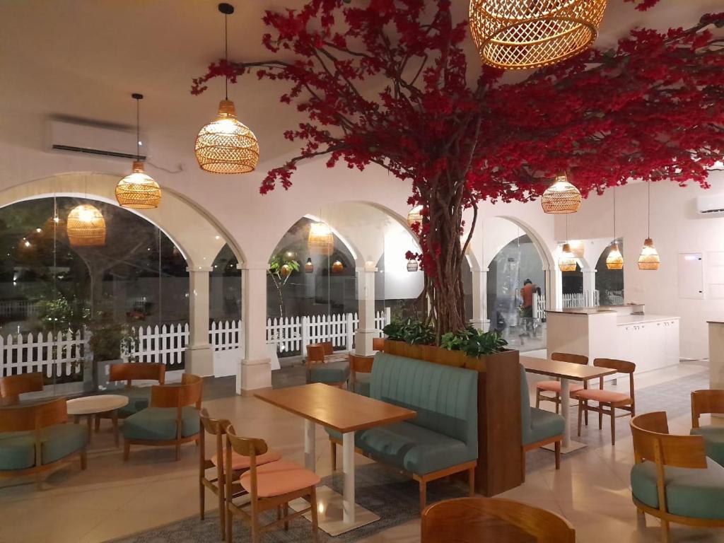 a restaurant with tables and chairs and a tree at Zeleny Santorini in Negombo