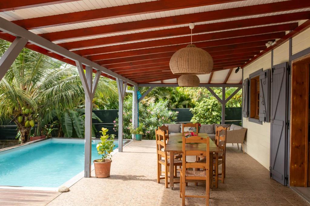 a patio with a table and chairs and a swimming pool at Evasion tropicale villa 6 personnes avec piscine in Saint-Louis