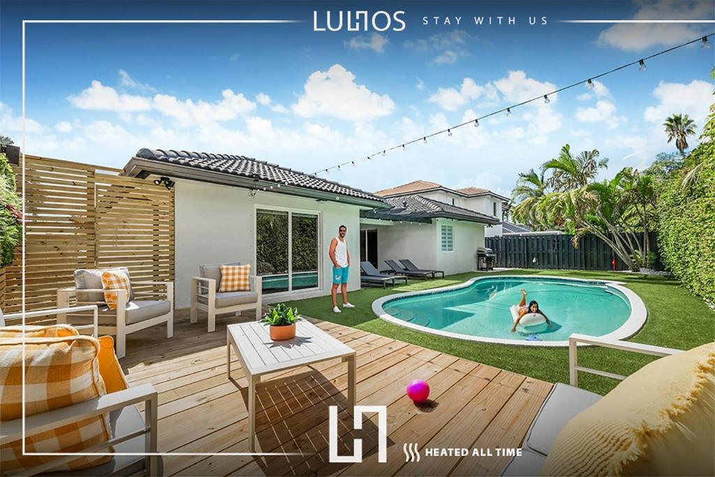 two people in the backyard of a house with a swimming pool at Deluxe Miami House w 5BR Mini Golf & Heated Pool L62 in Miami