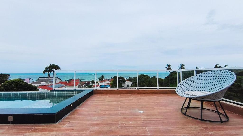 a chair on a balcony with a view of the ocean at Miray Exclusive - Praia dos Carneiros in Praia dos Carneiros