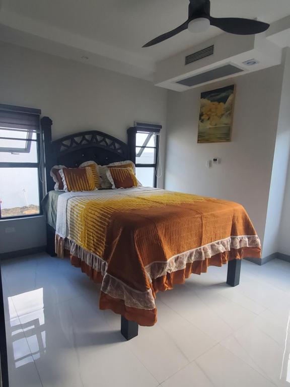 a bedroom with a bed with an orange comforter and two windows at Paradise in Paradisac in Richmond