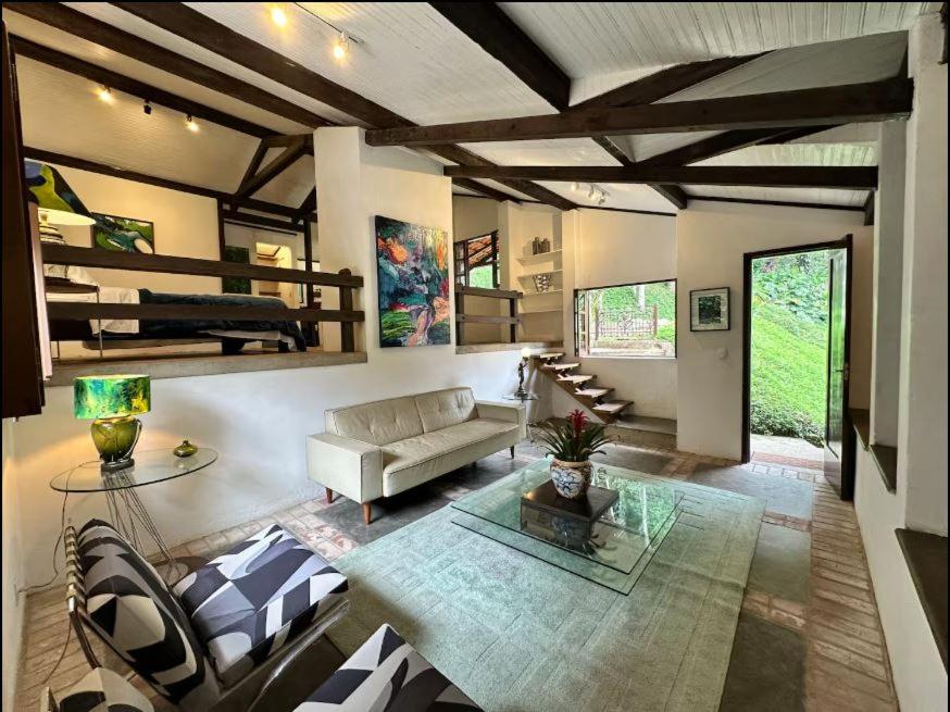 a living room with a couch and a loft bed at Chalé em Mata Atlântica no Coração de Petrópolis in Petrópolis