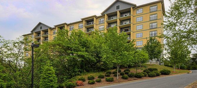 a large yellow apartment building with trees and a street at Mountain View Condo 1501 in Pigeon Forge