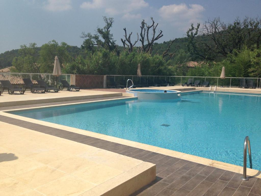 a large swimming pool with blue water in a yard at Appartement dans Residence – Le Domaine de Camiole in Callian