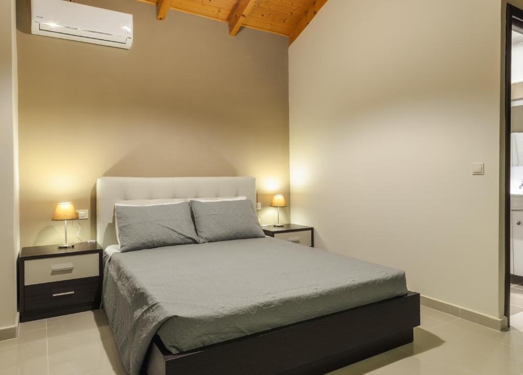 a bedroom with a bed with two night stands and two lamps at Eden Villas in Anafonítria