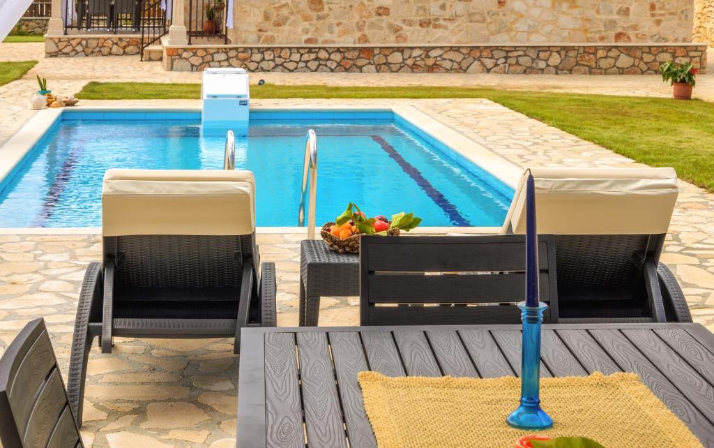 a pool with two chairs and a table and a umbrella at Eden Villas in Anafonítria