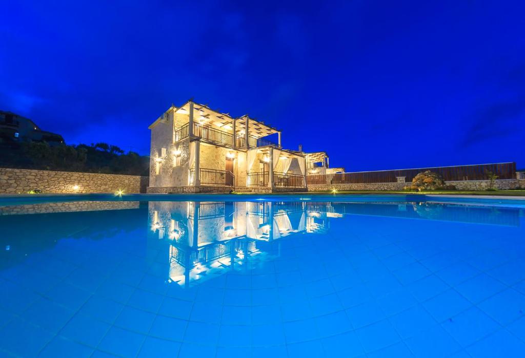 uma piscina à noite com uma casa ao fundo em Eden Villas em Anafonítria