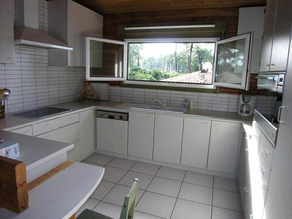 a kitchen with white cabinets and a window in it at Résidence 03134-lacanau Ocean - Chalet bois indépendant, 3 chambres, 6 personnes proche plage Lacanau océan MAE-0531 in Lacanau