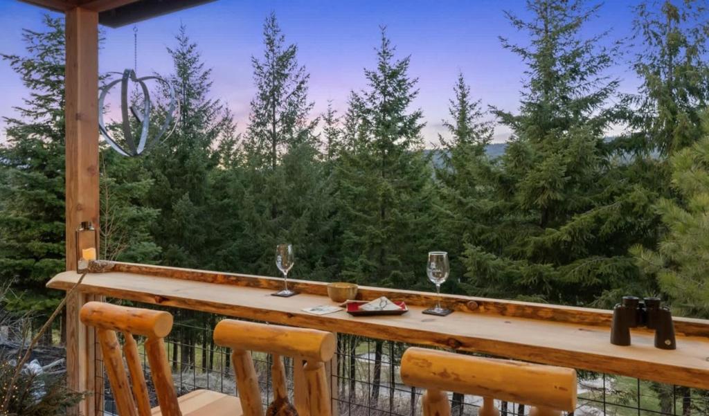 a table on a deck with a view of trees at Prospector Pines Treetop Escape in Suncadia- Fairway View, BBQ, Outdoor Fireplace, Smart TVs, Hi-speed Wi-Fi in Cle Elum