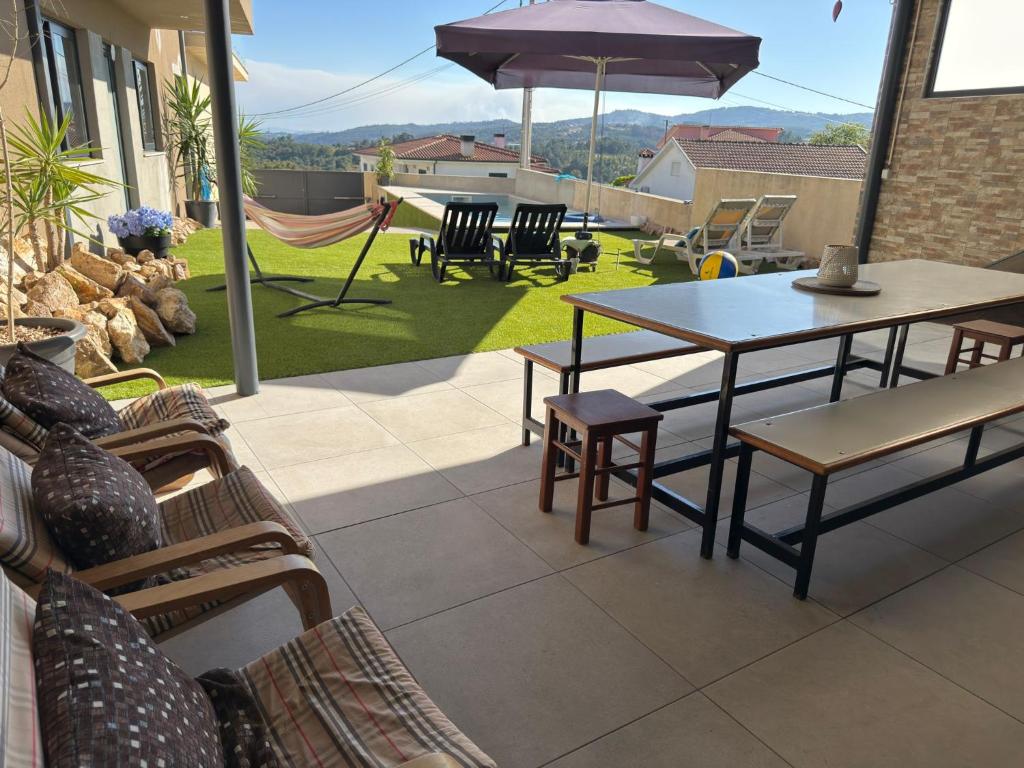 马尔科-德卡纳维泽斯Casa Moderna na Aldeia的带桌椅和遮阳伞的露台