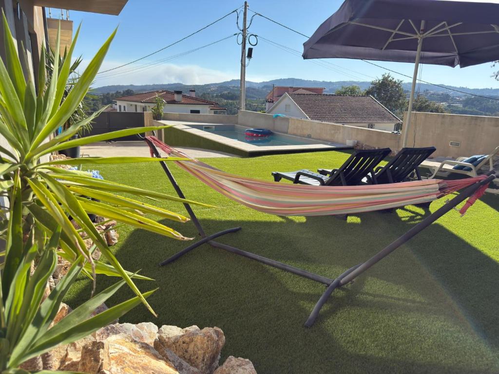 a hammock with chairs and an umbrella on a patio at Casa Moderna na Aldeia in Marco de Canaveses