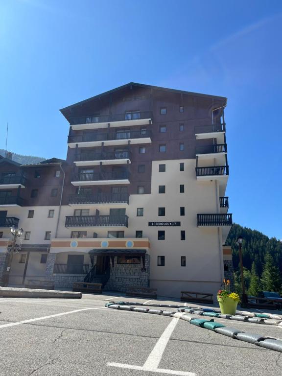 a large building with a parking lot in front of it at Le grand argentier - valfrejus in Modane