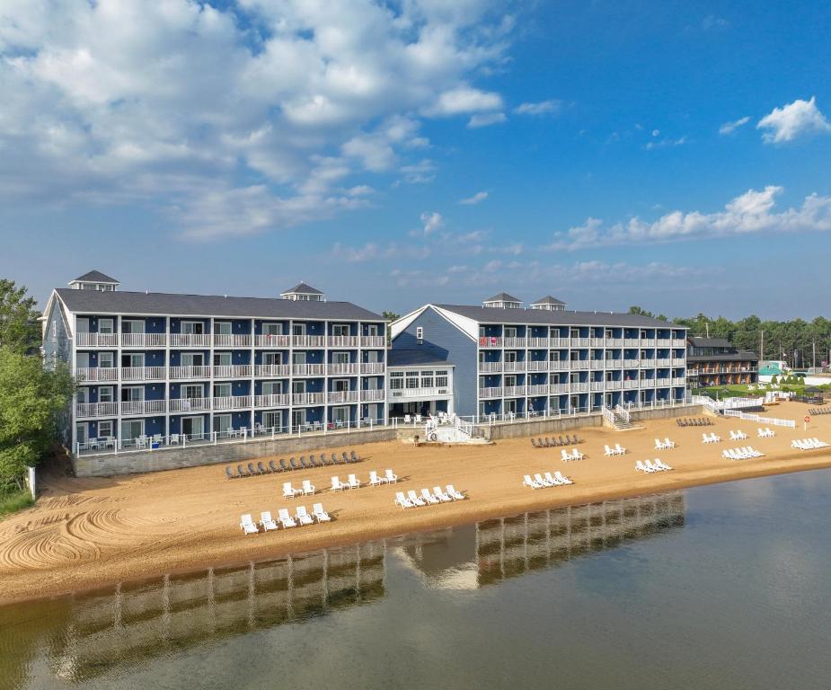 a hotel with a beach with white lounge chairs at The Baywatch Resort in Traverse City