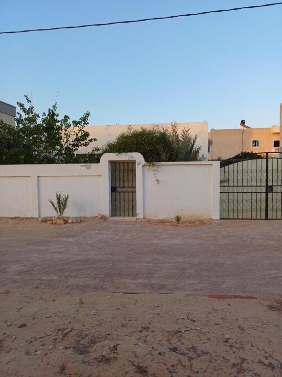 a white building with a gate and a fence at Baraka in Aghīr