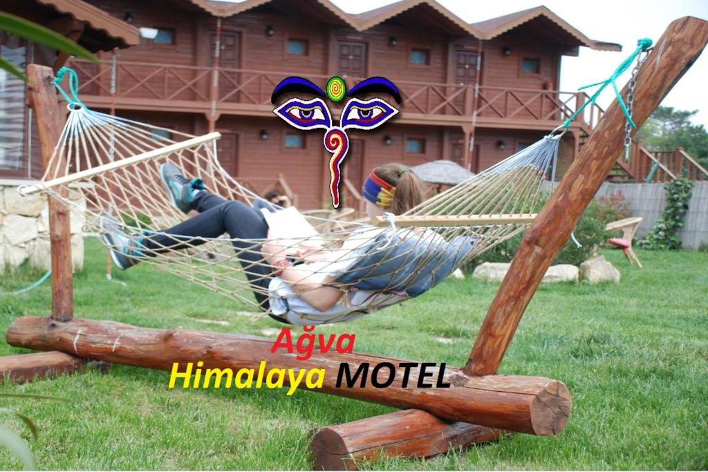 una mujer tendida en una hamaca en un patio en Agva Himalaya Motel, en Agva