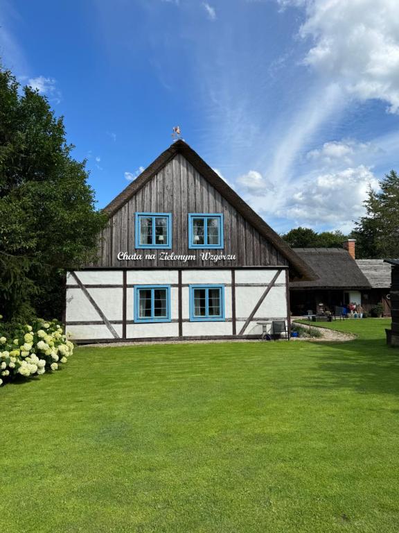 a large barn with blue windows in a yard at Chata na Zielonym Wzgórzu in Garcz