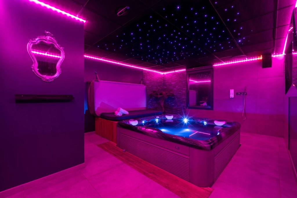 Habitación con bañera de hidromasaje con luces rosas. en Espace évasions Loft love LOVE ROOM, en Toulouse
