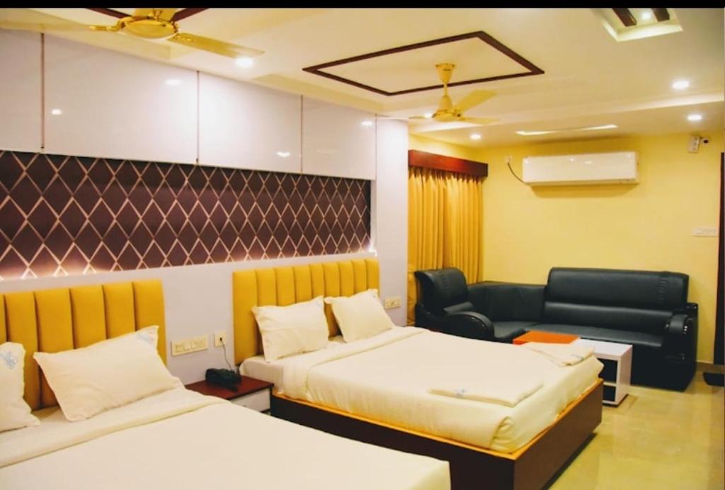 a hotel room with two beds and a couch at HoTEL NARMADA GRAND in Vijayawāda