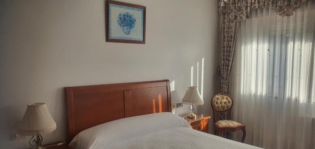 ein Schlafzimmer mit einem Bett und einem Stuhl und einem Fenster in der Unterkunft Edificio Zoqueiro in San Cosme de Barreiros