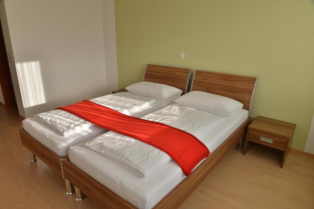 a bed with a red blanket on top of it at Motel Mühle in Wollerau
