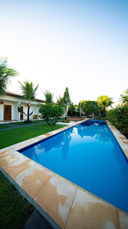 卡姆布库Bosque Cumbuco Pousada的房子前面的一个蓝色大游泳池