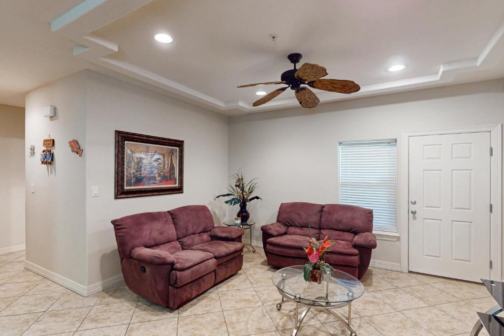 a living room with two chairs and a ceiling fan at Sea Glass Condominiums 2 in South Padre Island