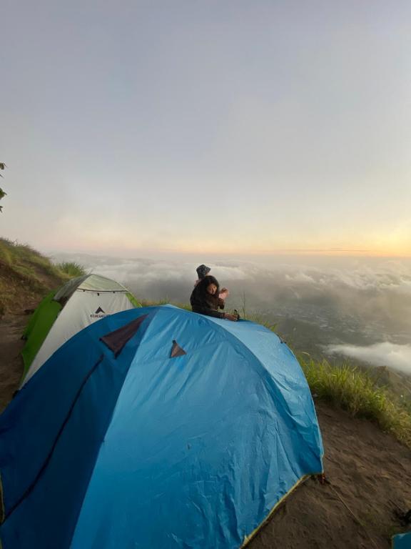 クブペンロカンにあるMount Batur Camping on Summitの山のテントの上に座っている男性