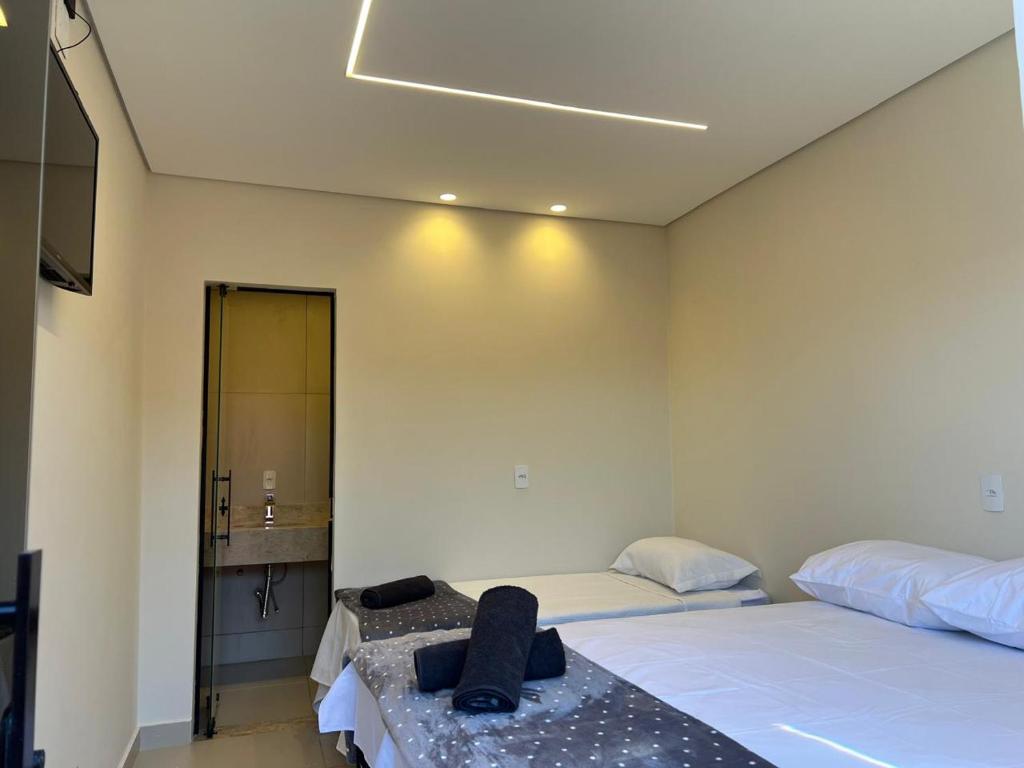 a room with two beds and a bathroom with a mirror at suítes Pousada Catuira 1 in Araxá