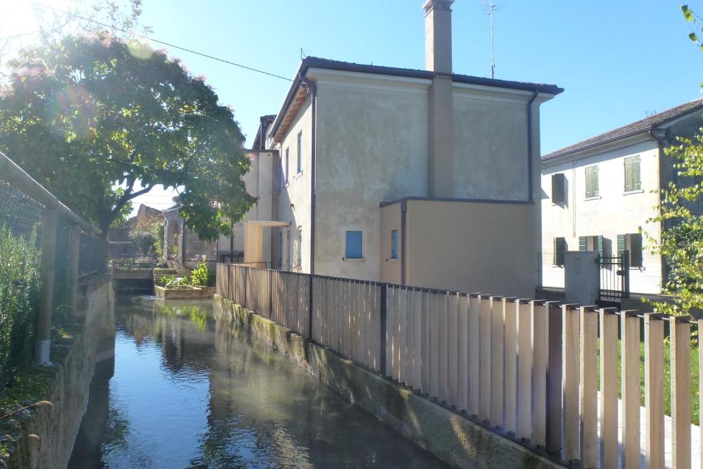 a canal in a city with houses and a fence at Casa Kaletheia in Volpago del Montello