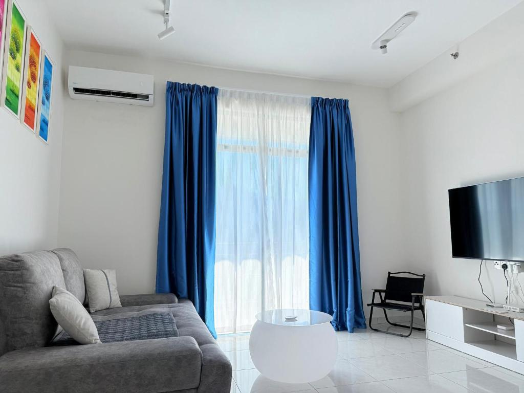 a living room with a couch and blue curtains at The Sun Executive Suite - Dolphin's Home in Bayan Lepas