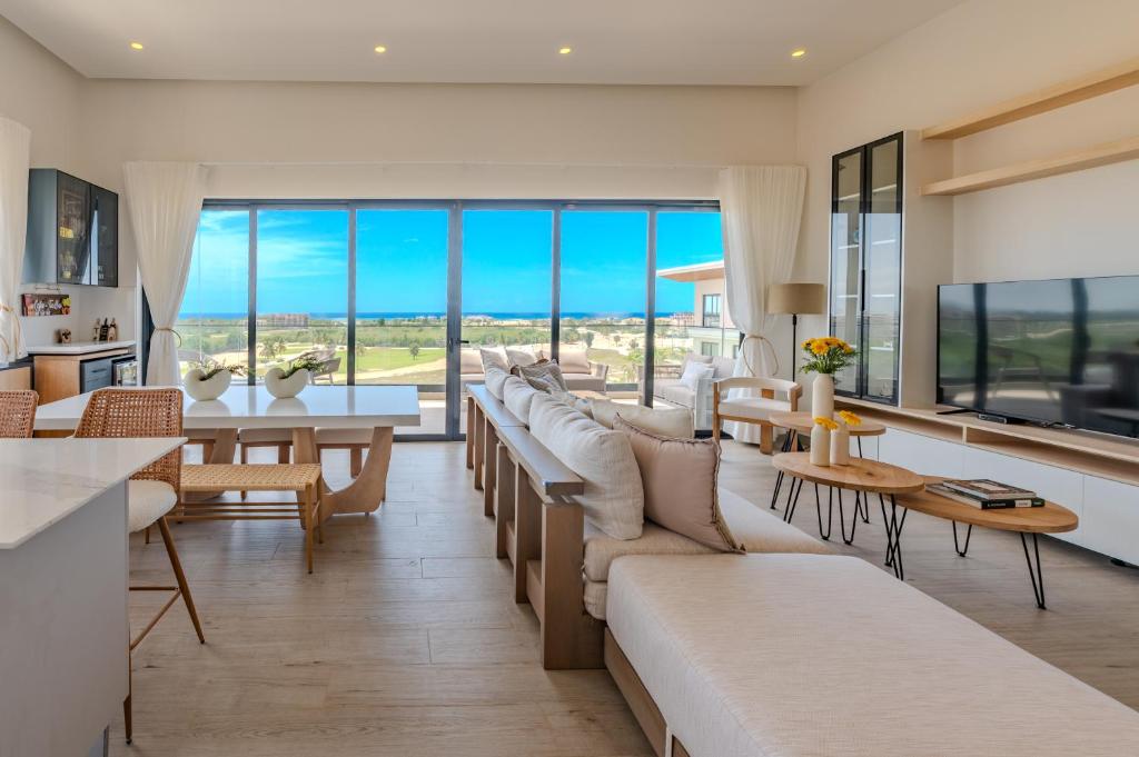 Una sala de estar con sofás, mesas y ventanas. en New! Luxury PH with Pool Golf & Ocean Views, en Punta Cana