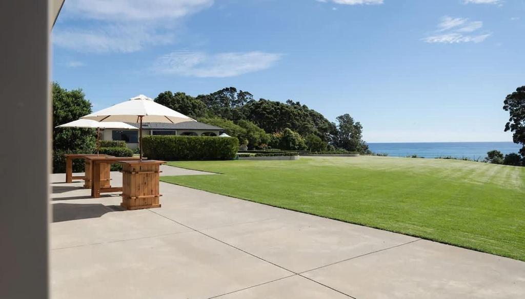 a picnic table with an umbrella on a lawn at Bay View Terrace Studio 3 in Tataraimaka